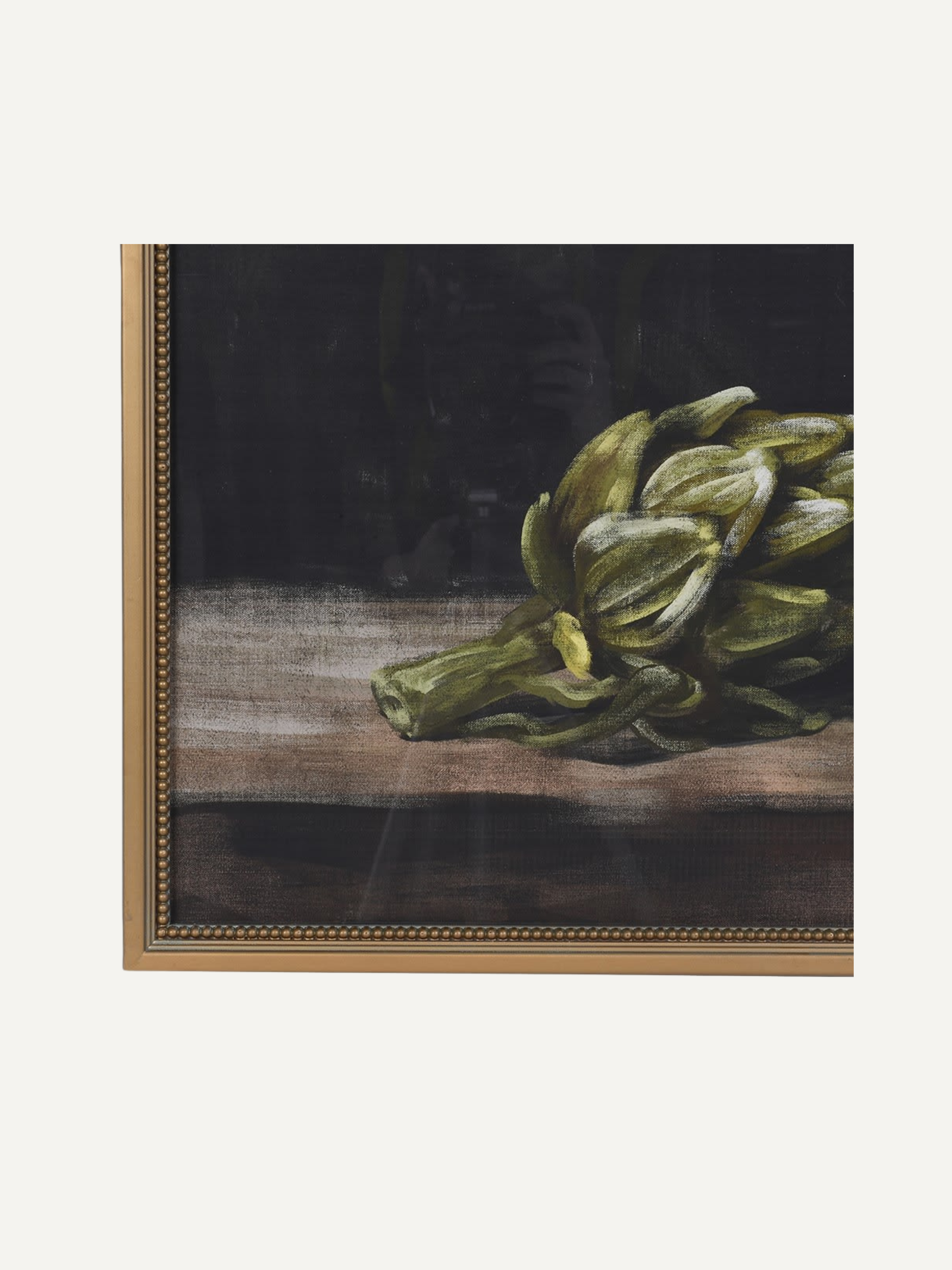 Framed artwork of a green artichoke on a wooden surface with a dark background