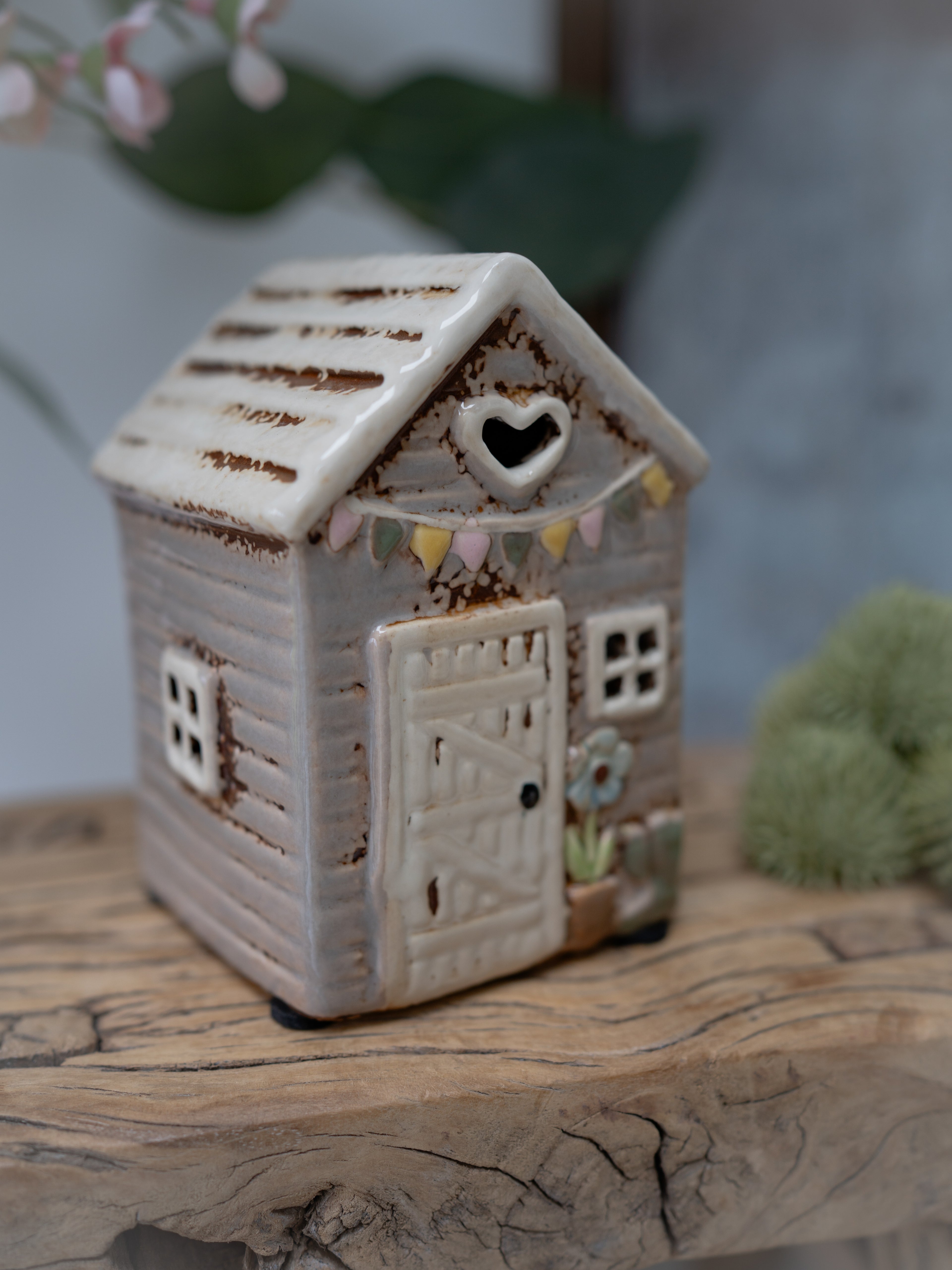 Ceramic house-shaped lantern on a wooden surface with a blurred background