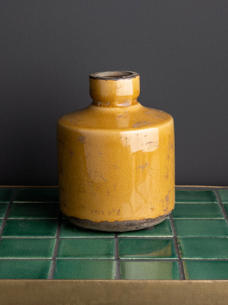MUSTARD ceramic bottle on a green tiled surface with a dark gray background