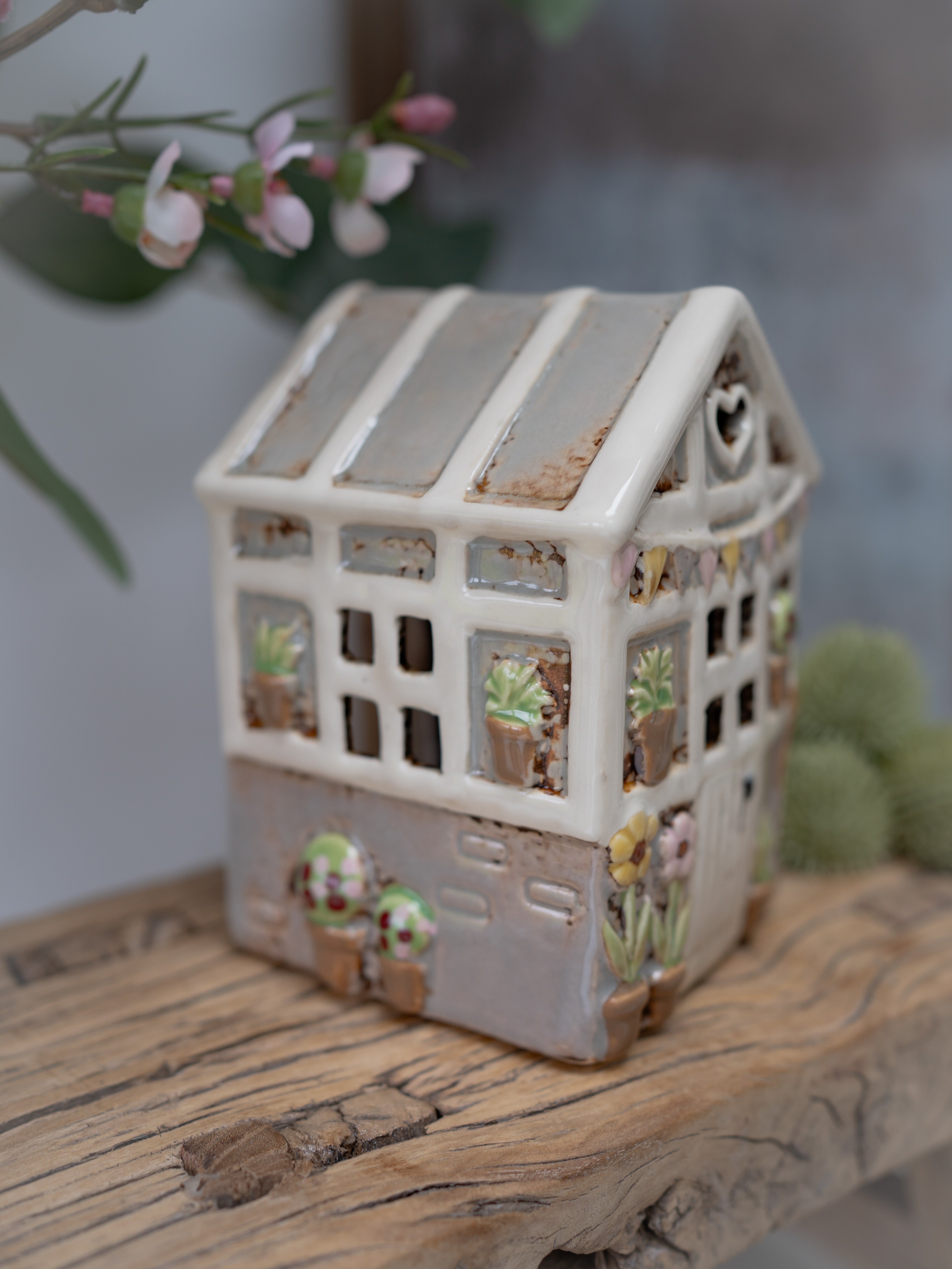 Decorative ceramic house with plant designs on a wooden surface