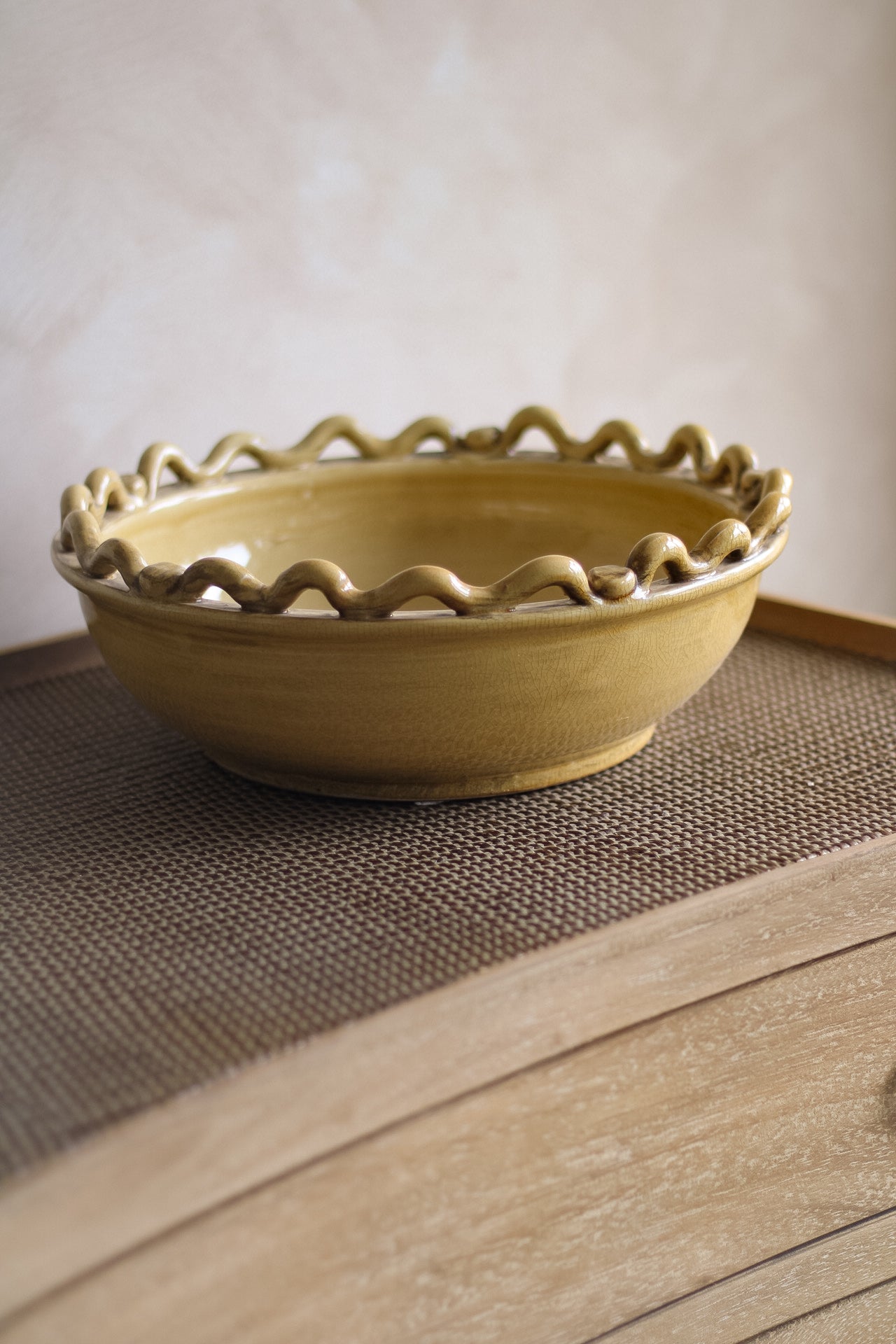 Yellow ceramic bowl with wavy edge on a wooden surface
