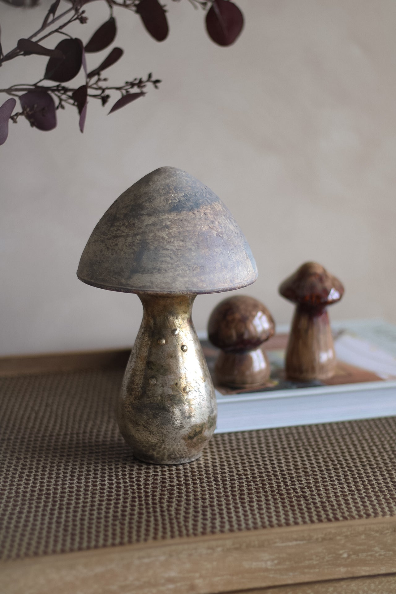 Decorative copper mushrooms on a textured surface with a neutral background