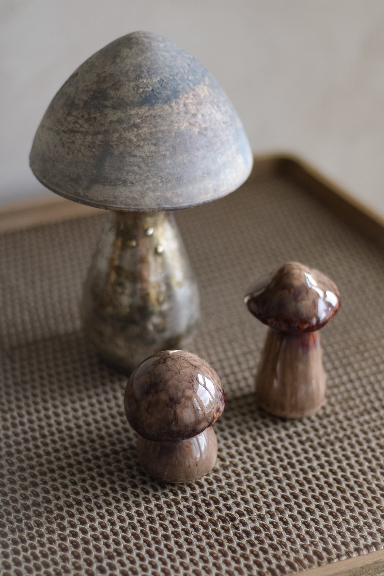 Three ceramic and glass mushroom figurines on a textured surface