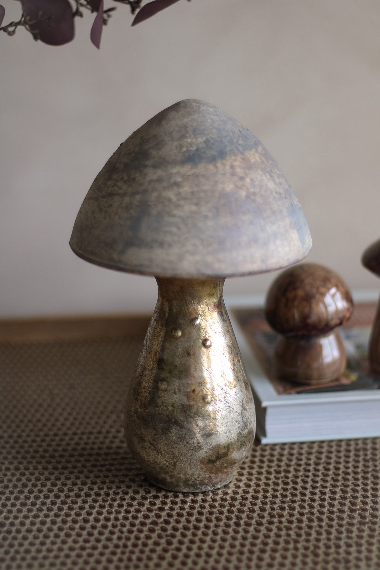 Decorative metallic mushroom on a textured surface with a neutral background