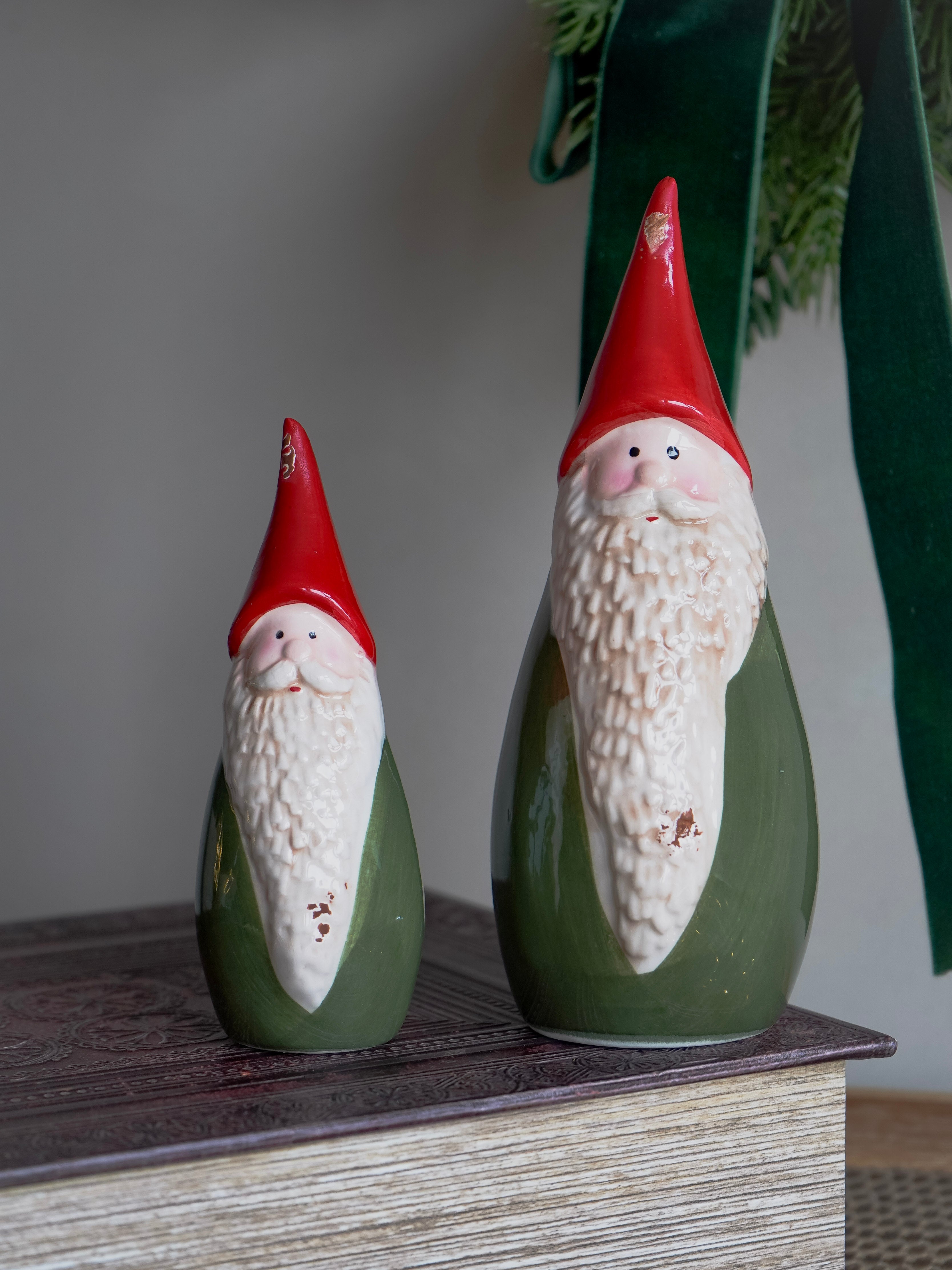 Two ceramic gnomes with red hats on a wooden surface.