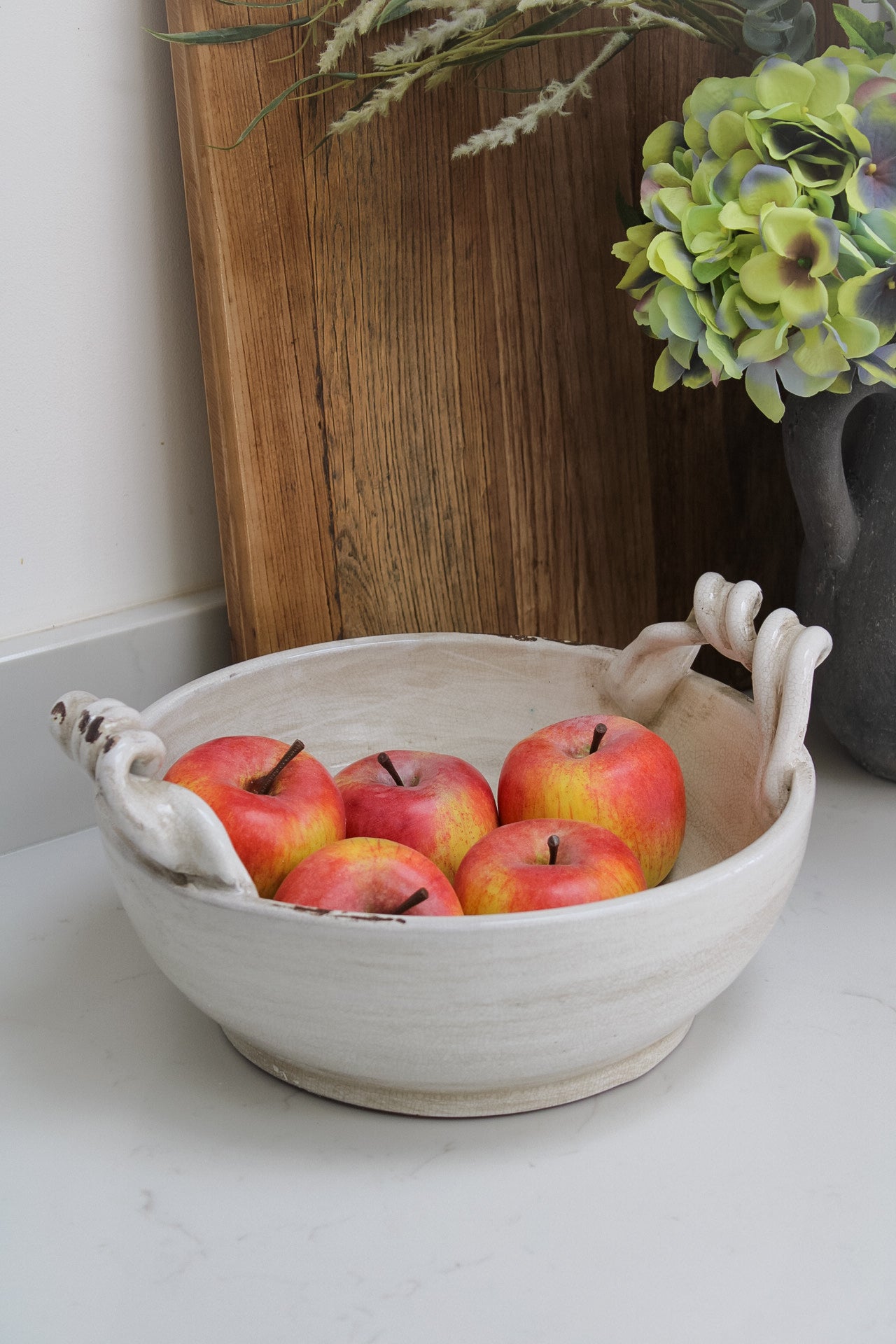 Twisted handle cream ceramic decorative fruit bowl filled with faux red apples