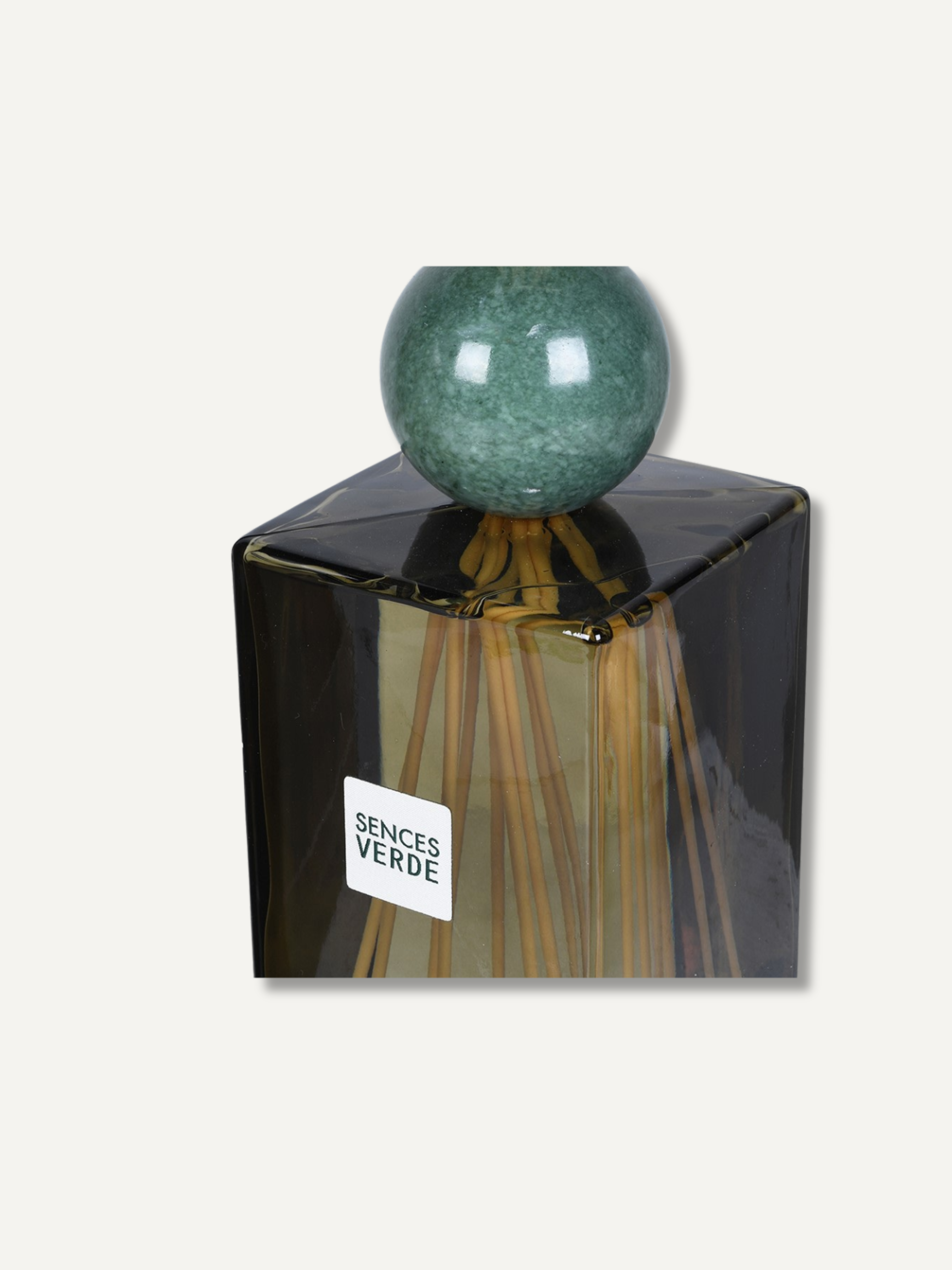 A Sences Verde reed diffuser with a dark green glass bottle, a round green marble stopper, and natural reed sticks visible inside, set against a plain off-white background.