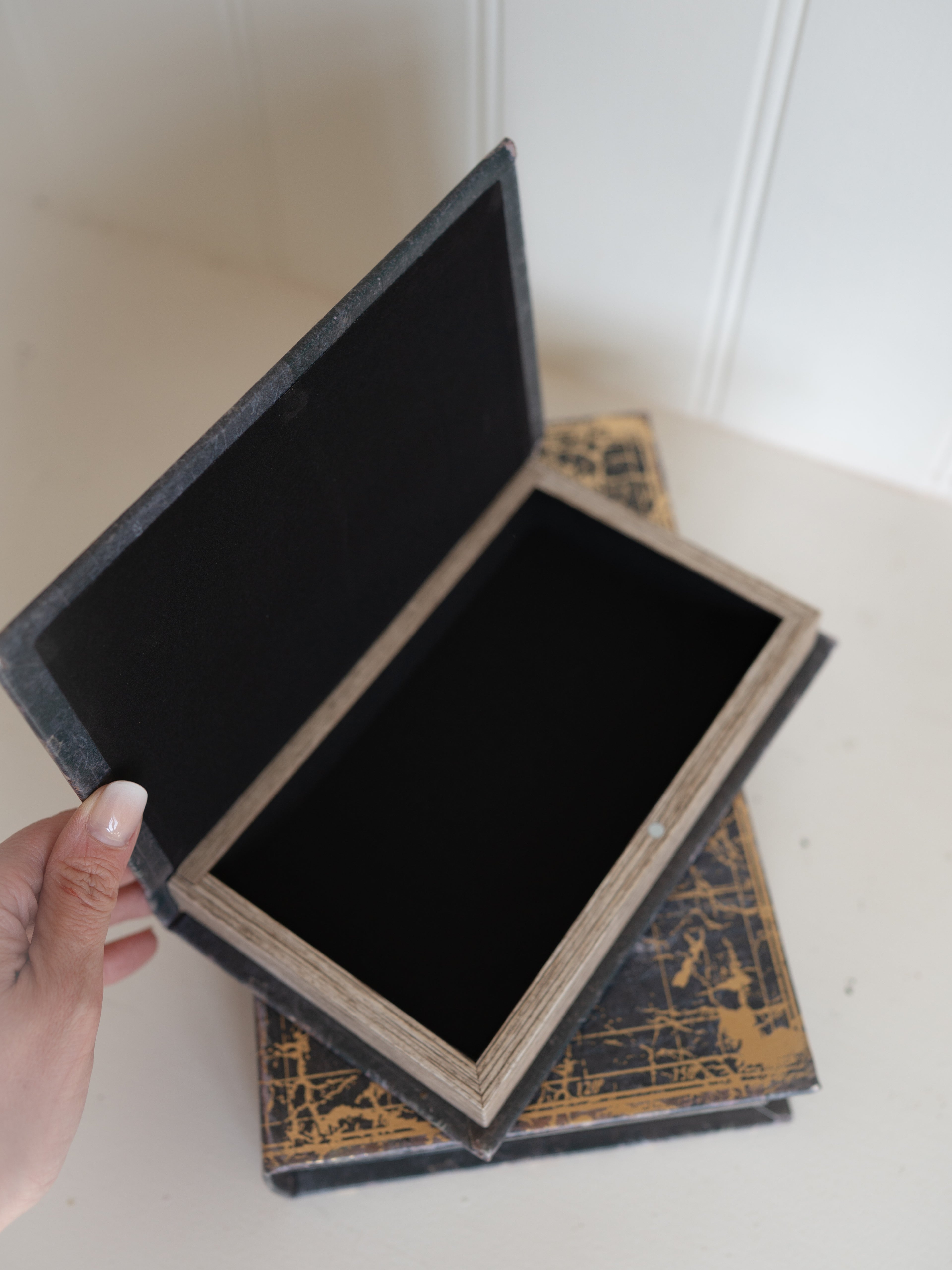 Open storage book box with gold design on a white surface