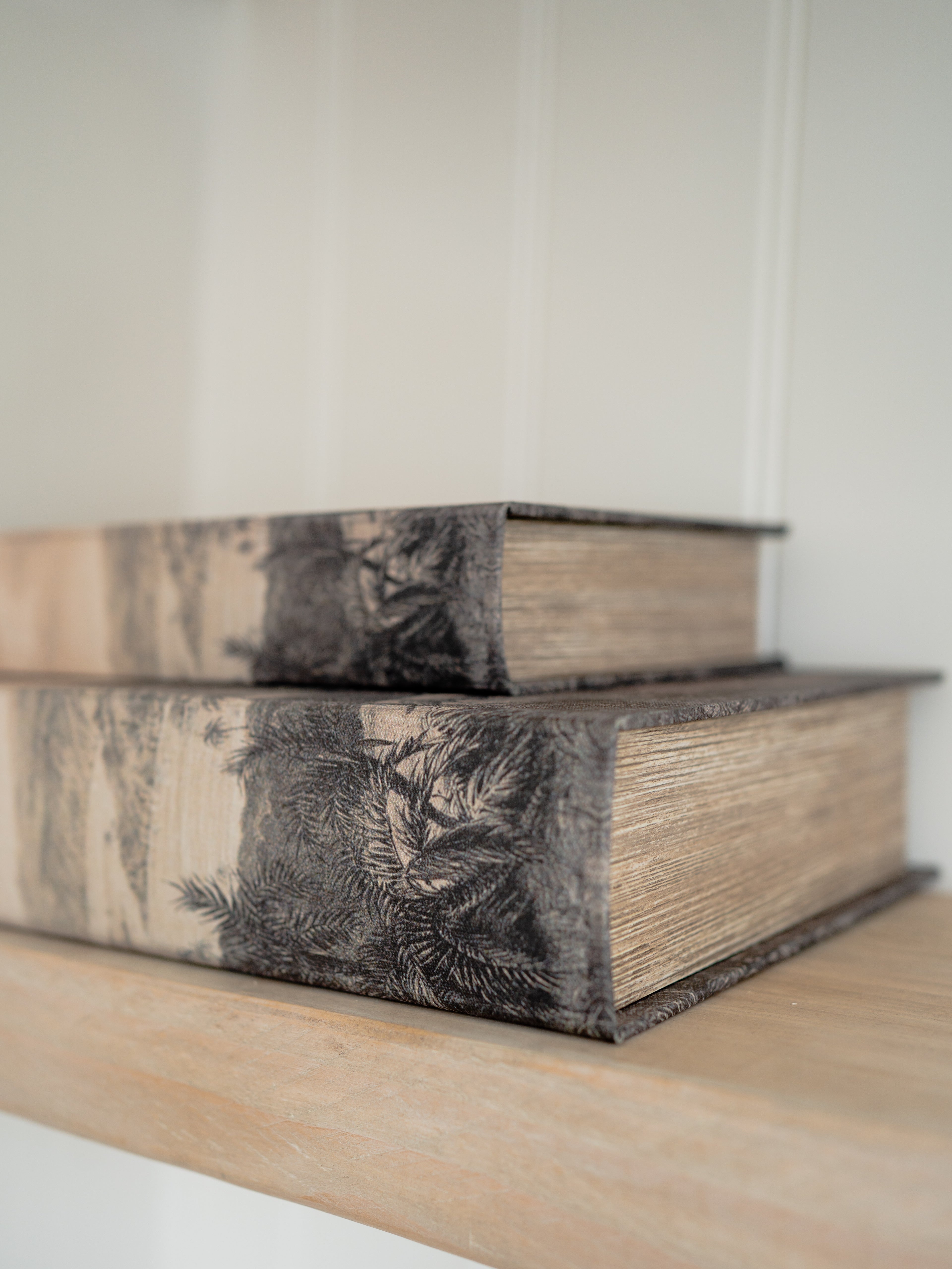 Two decorative storage books with floral patterns on a wooden surface.