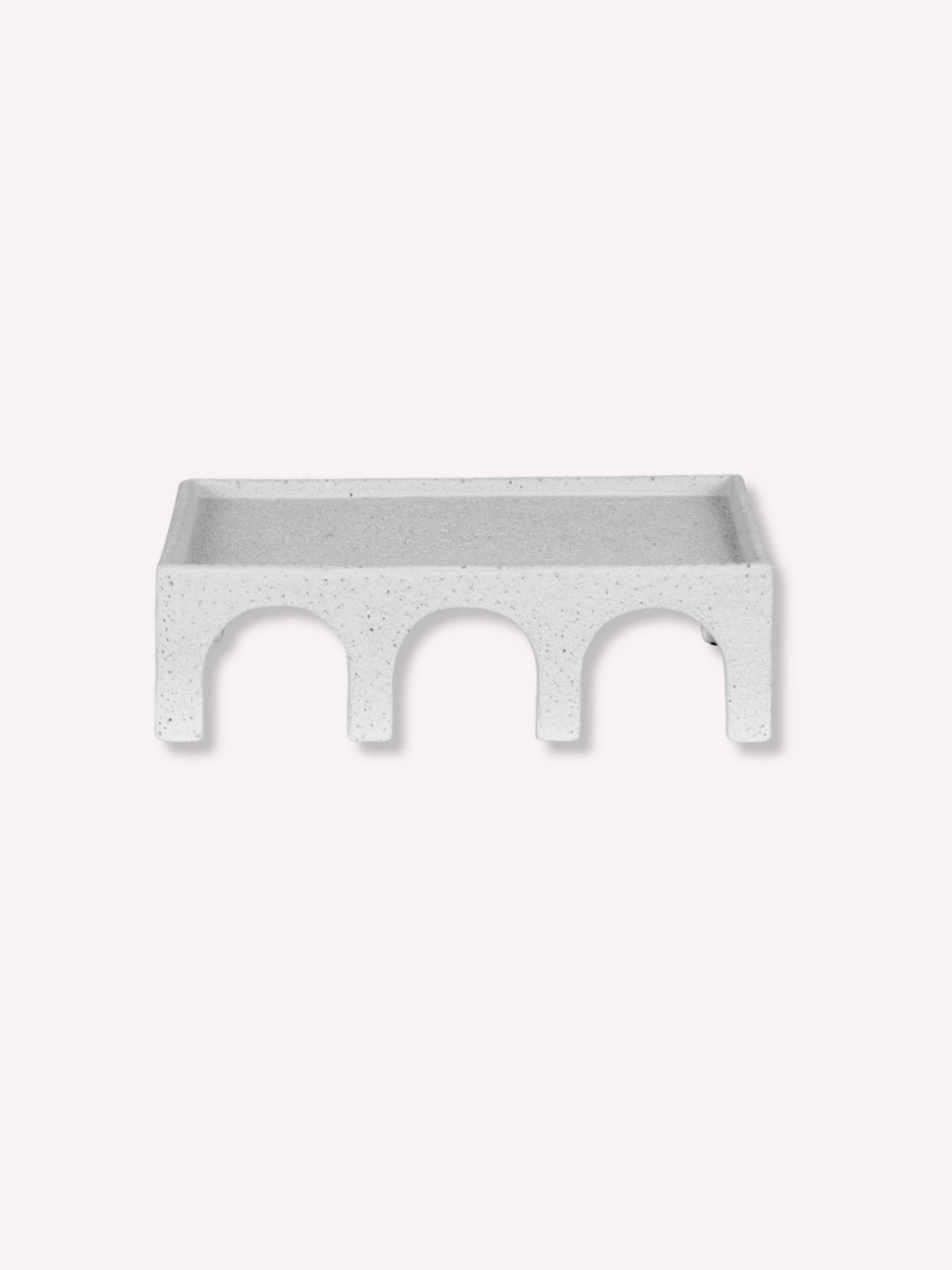 A rectangular white speckled tray with three arched cutouts underneath, shown against a solid off-white background.