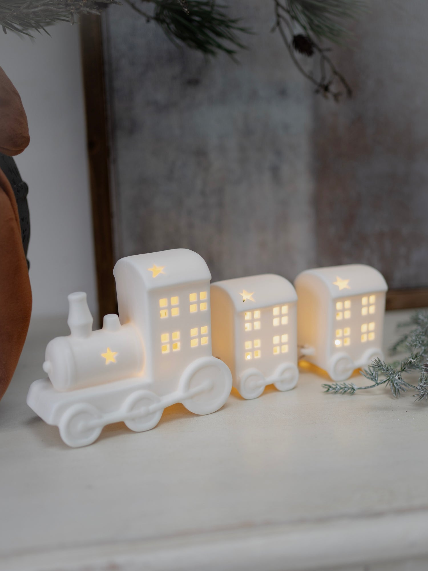 White ceramic train decoration with lit-up windows on a white surface.