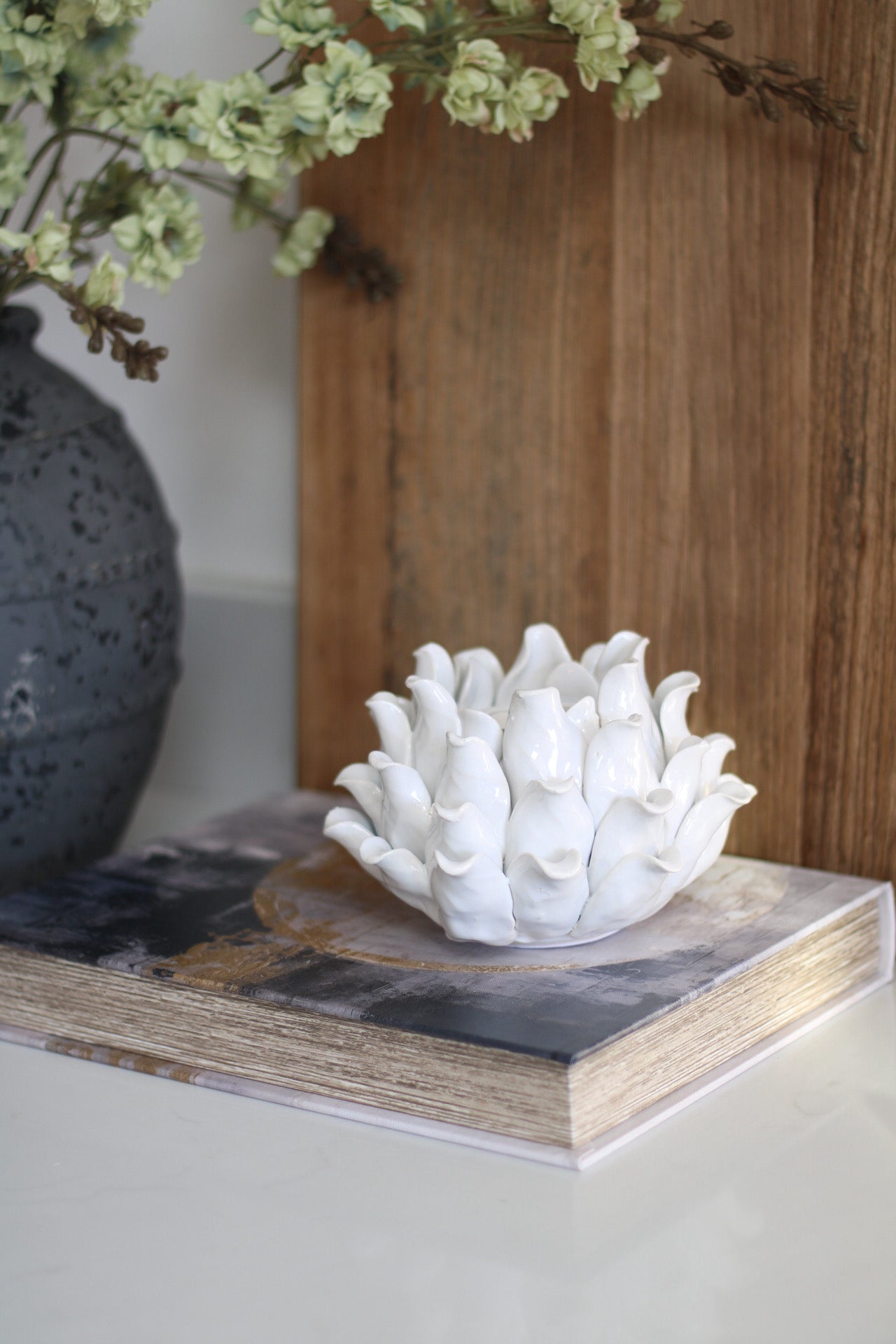 White flower-like sculpture on a wooden surface with a blurred background