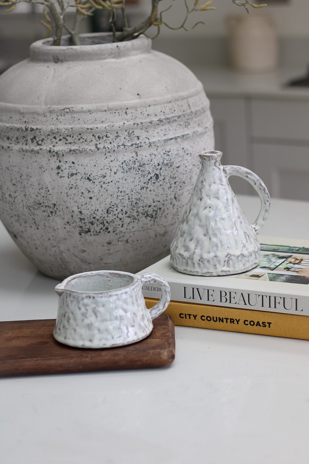 Decorative white mottled terracotta pot on a surface with a coffee table books in the background