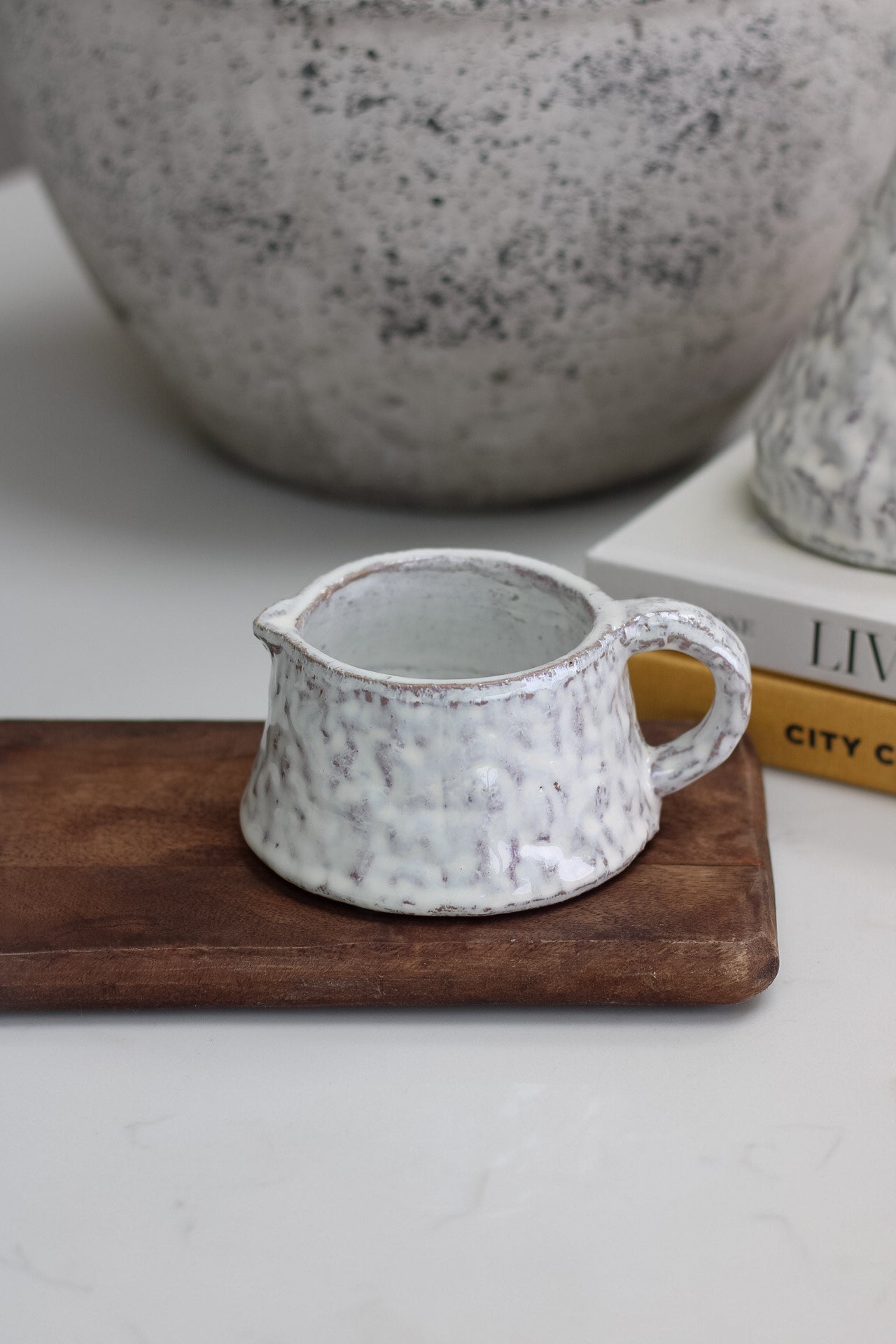 White mottled terracotta pot on a wooden tray with a blurred background
