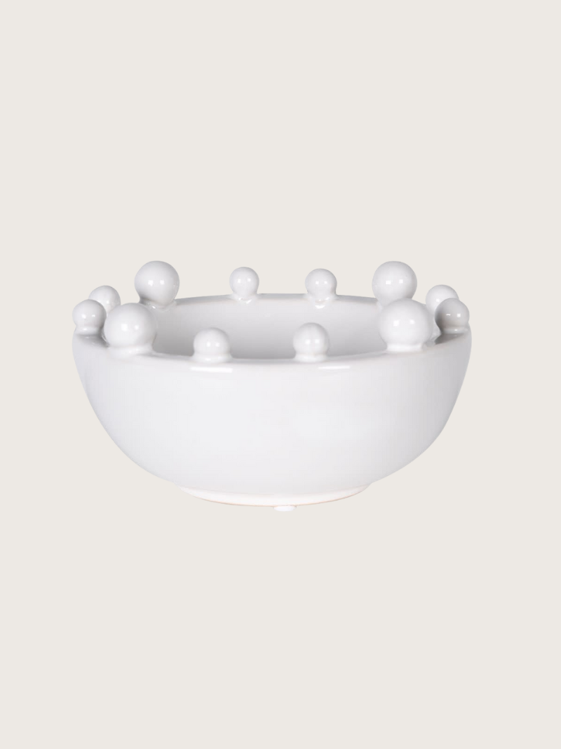 White ceramic bowl with bobble protrusions on a light beige background