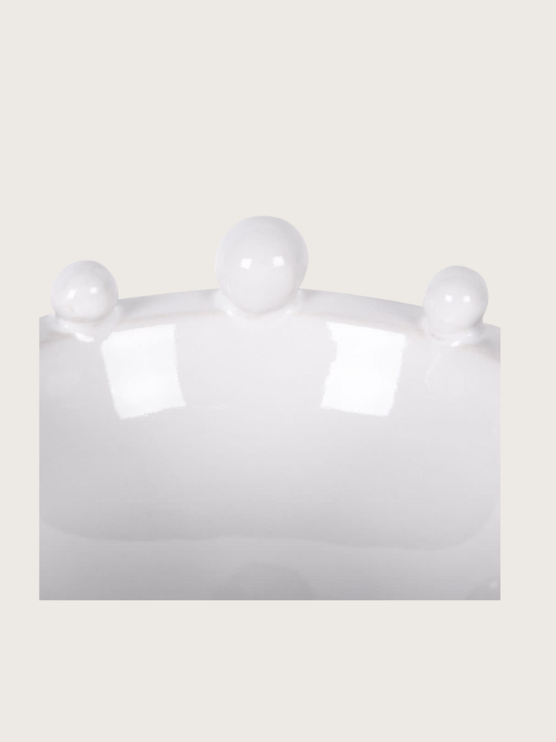 White ceramic bobble bowl with three spherical bulbs on a beige background