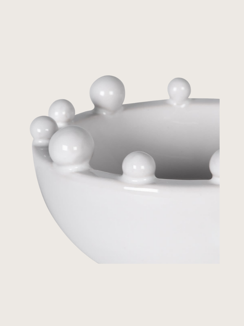 White ceramic bowl with bobble protrusions on a light gray background