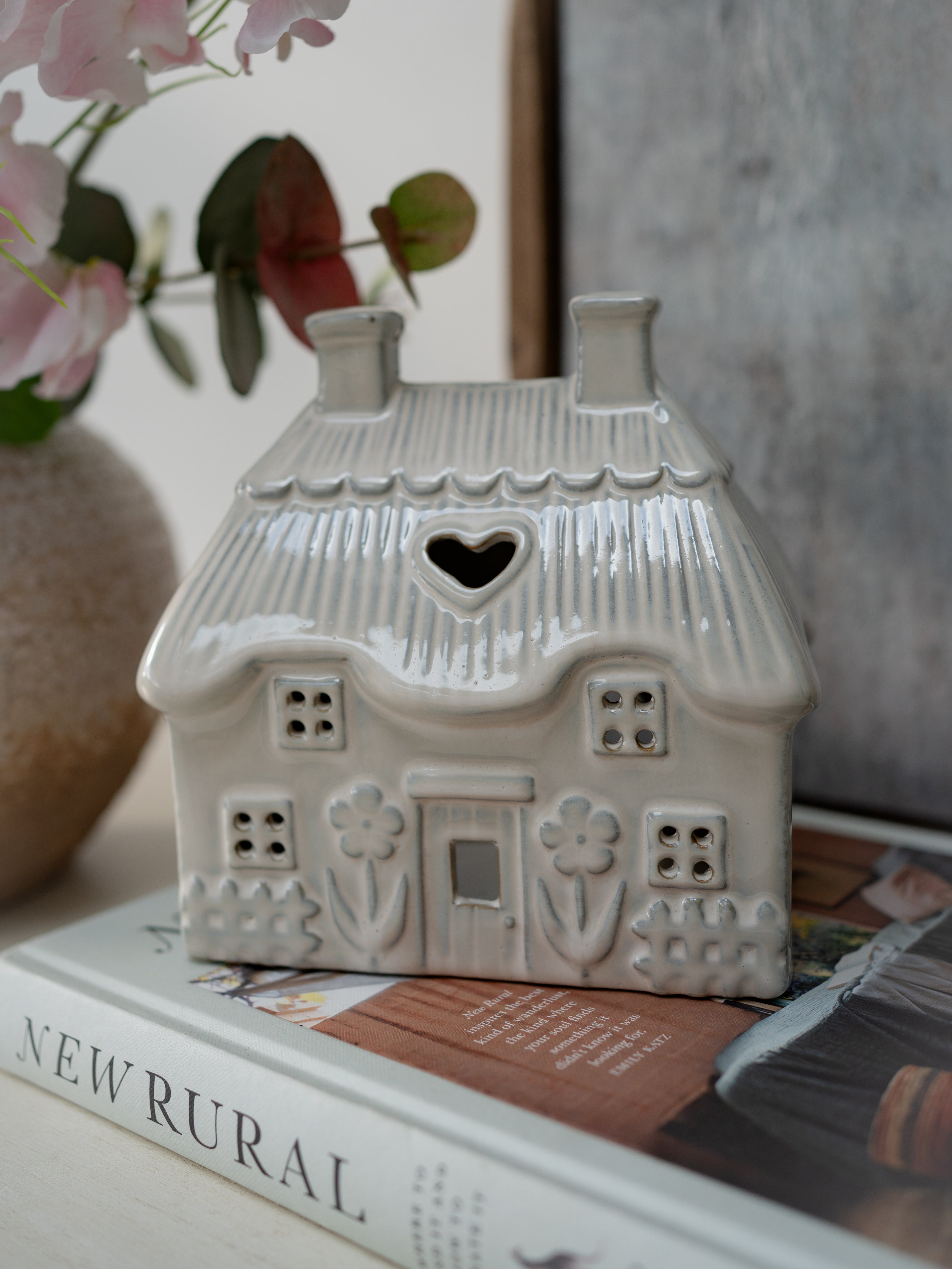 Decorative ceramic house with a heart-shaped window on top of a book