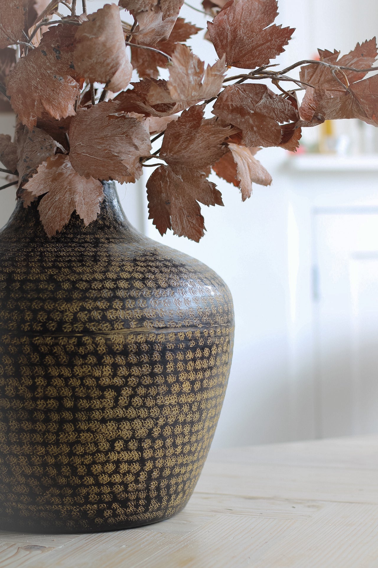 up close of etched details of hammered metal pot. Elegant vase to introduce rich tones to your home decor.