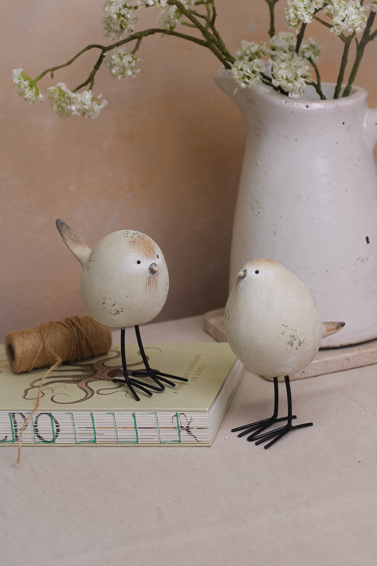 A set of two decorative stone-textured birds with long black legs, placed on a kitchen countertop.