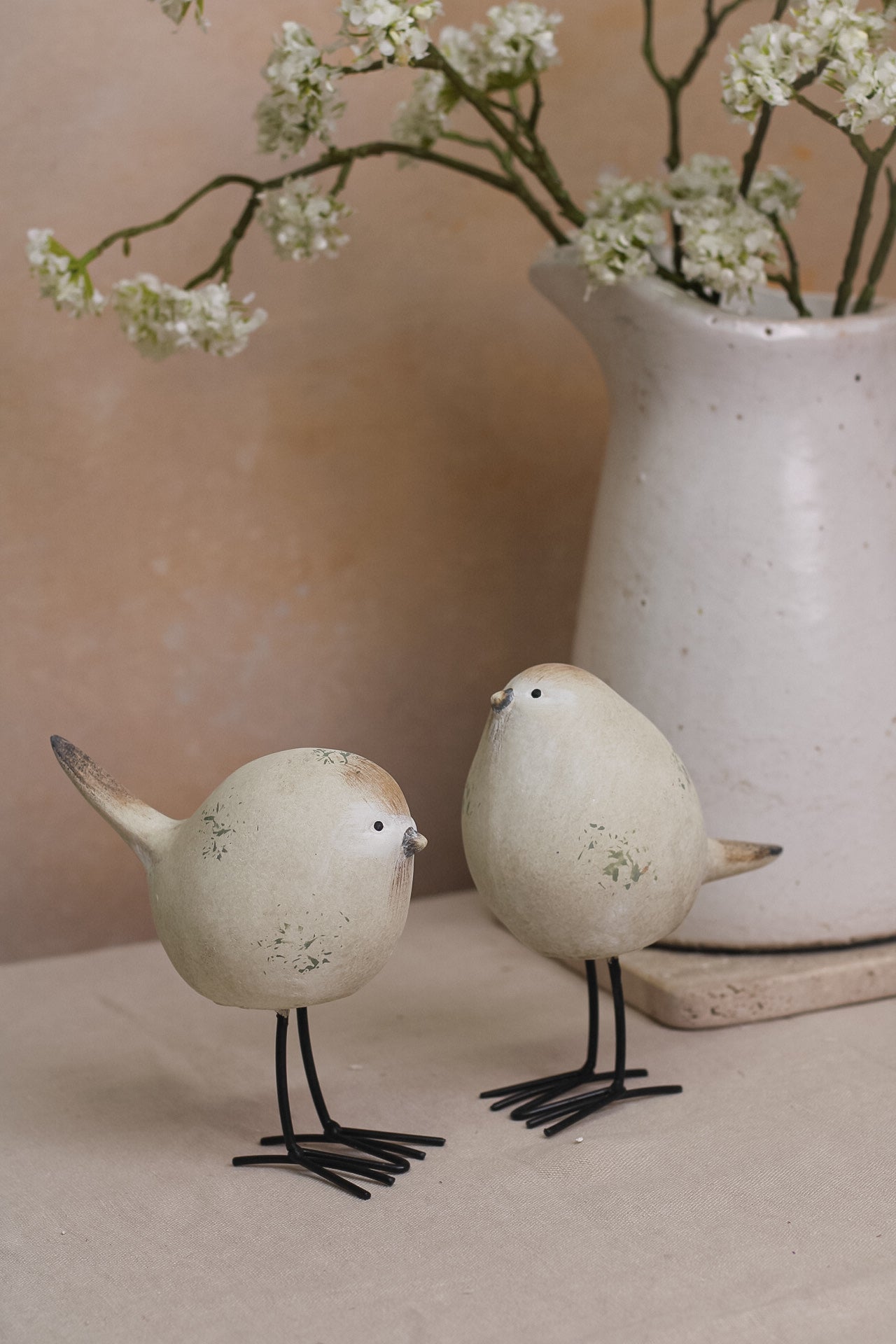 A set of two decorative stone-textured birds with long black legs, placed on a kitchen countertop.