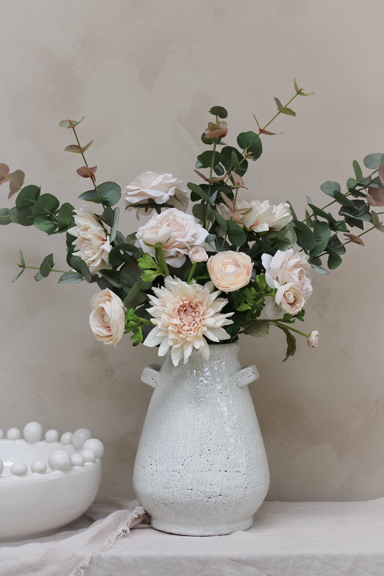 rustic white vase filled with powder pink faux flowers and blush eucalyptus