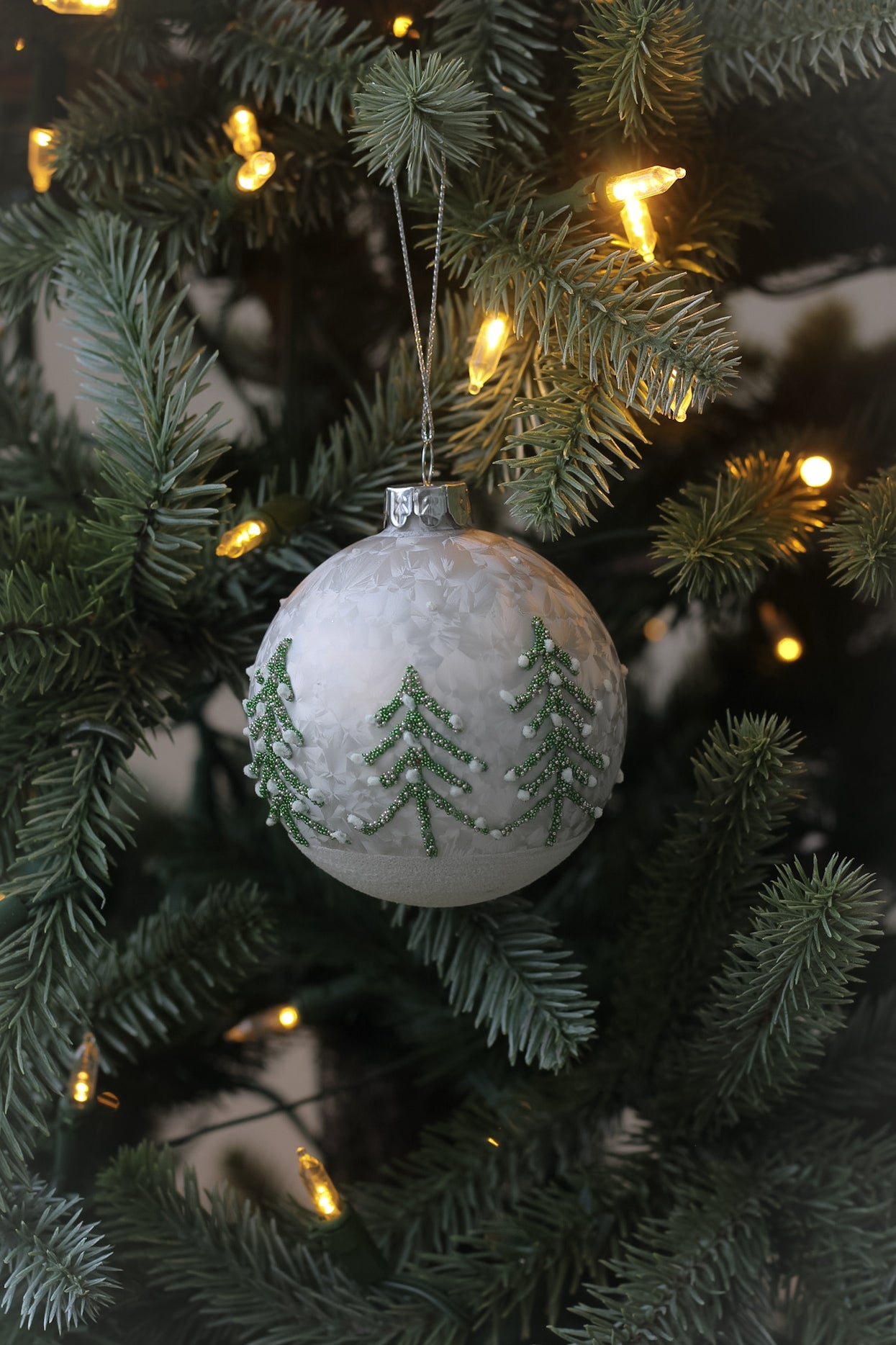 Elegant glass christmas tree bauble with delicate collection of christmas trees