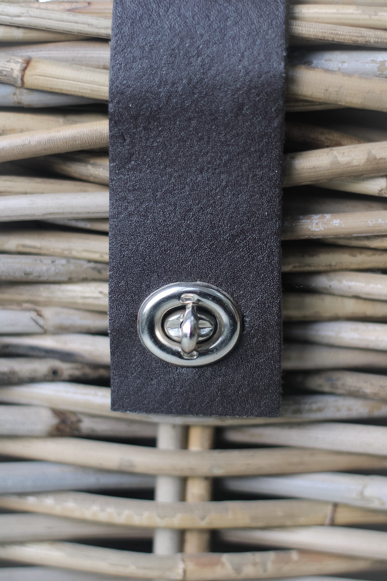 upclose of leather straps on wicker storage trunk