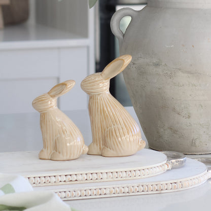 close up of Neutral Sitting Ribbed Bunny sat on styling boards with a rustic grey vase in the background