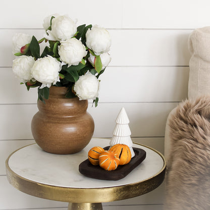 faux white peonies in vase with ceramic christmas tree and dried orange