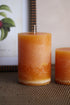 Two orange candles on a textured surface with a blurred background