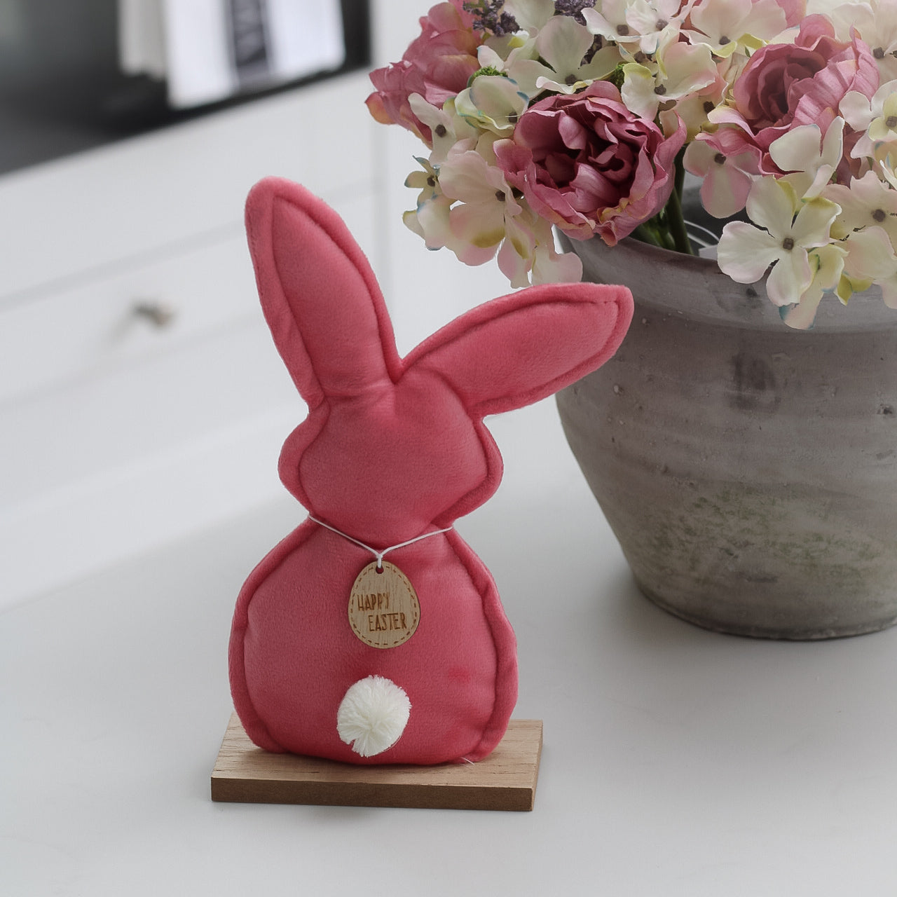Pink velvet bunny on wooden stand with happy easter tag
