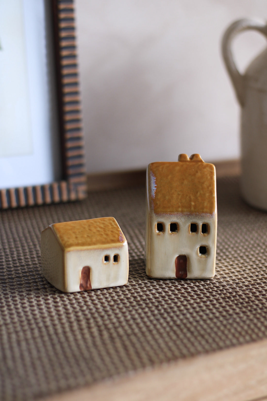 Two small ceramic house models on a textured surface with a blurred background.