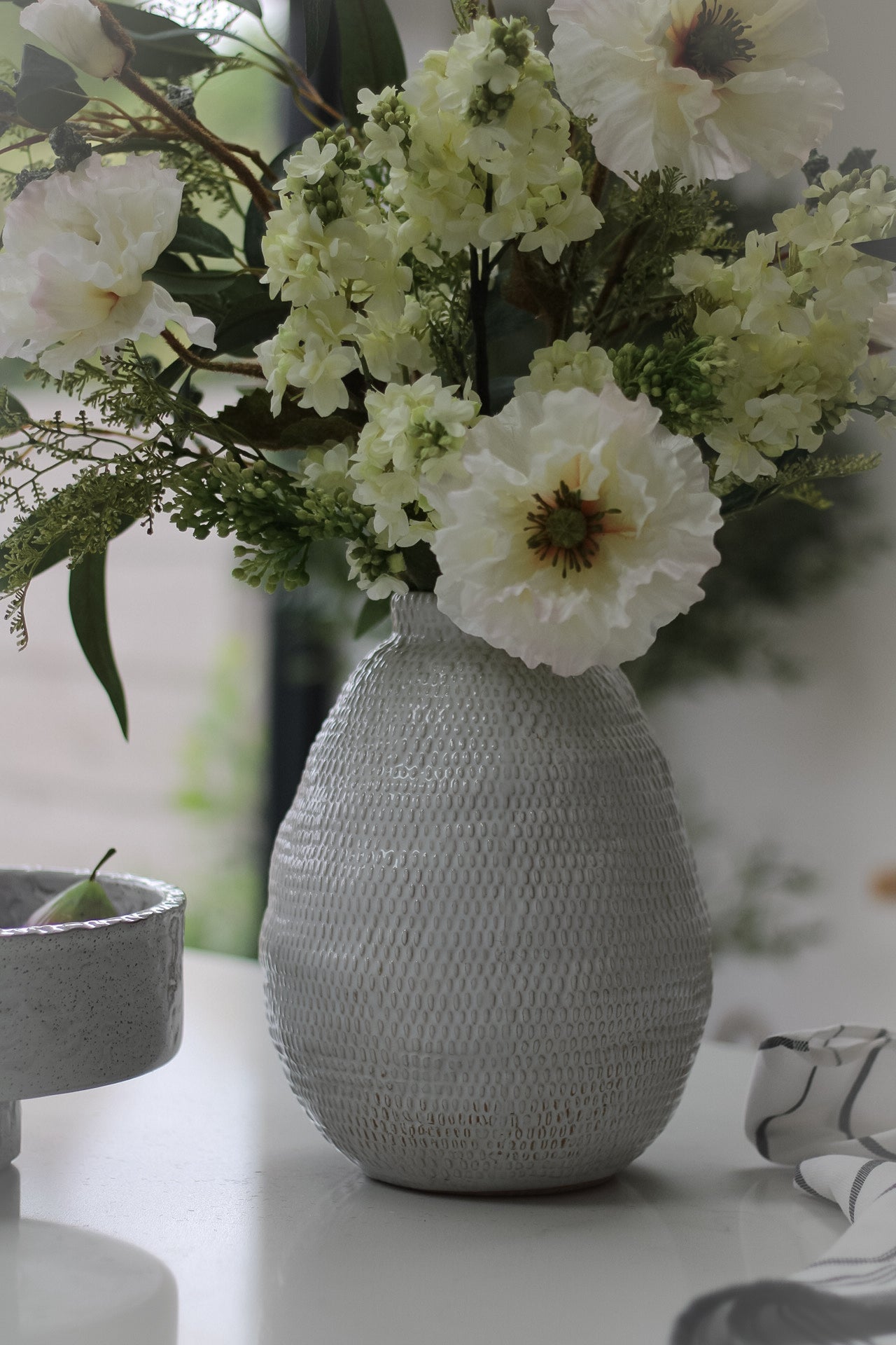 Faux flower arrangement in grey ceramic vase