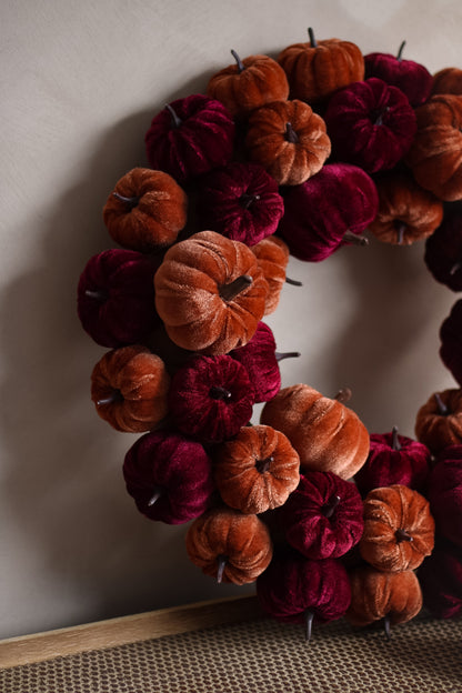 Decorative wreath made of orange and red pumpkins on a neutral background