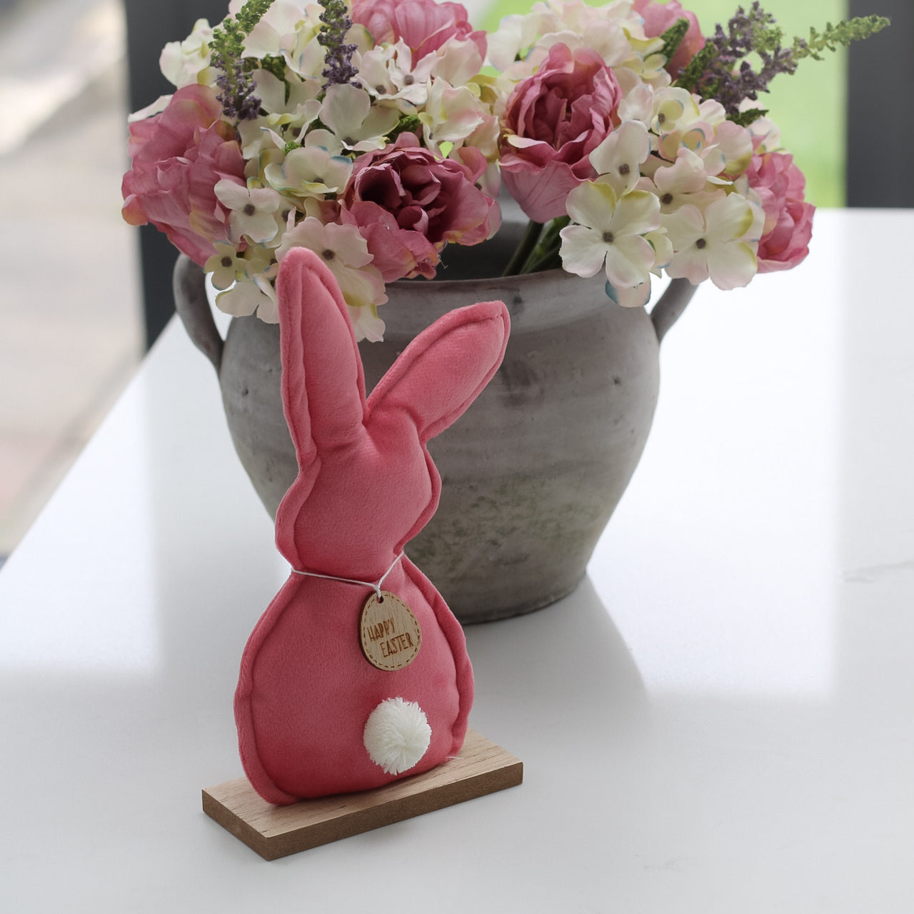 Pink velvet bunny on wooden stand with happy easter tag
