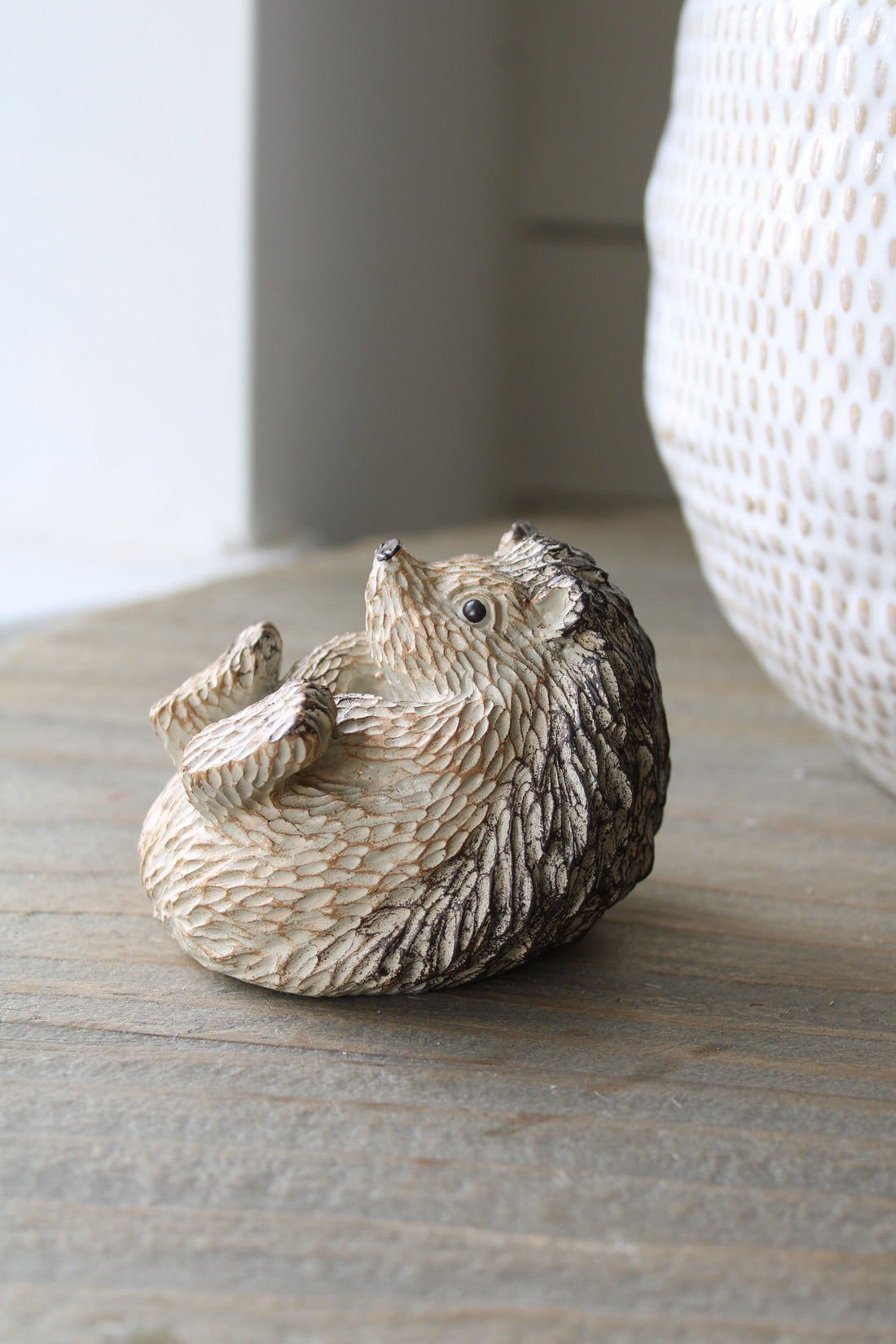 Decorative hedgehog figurine on a wooden surface with a neutral background