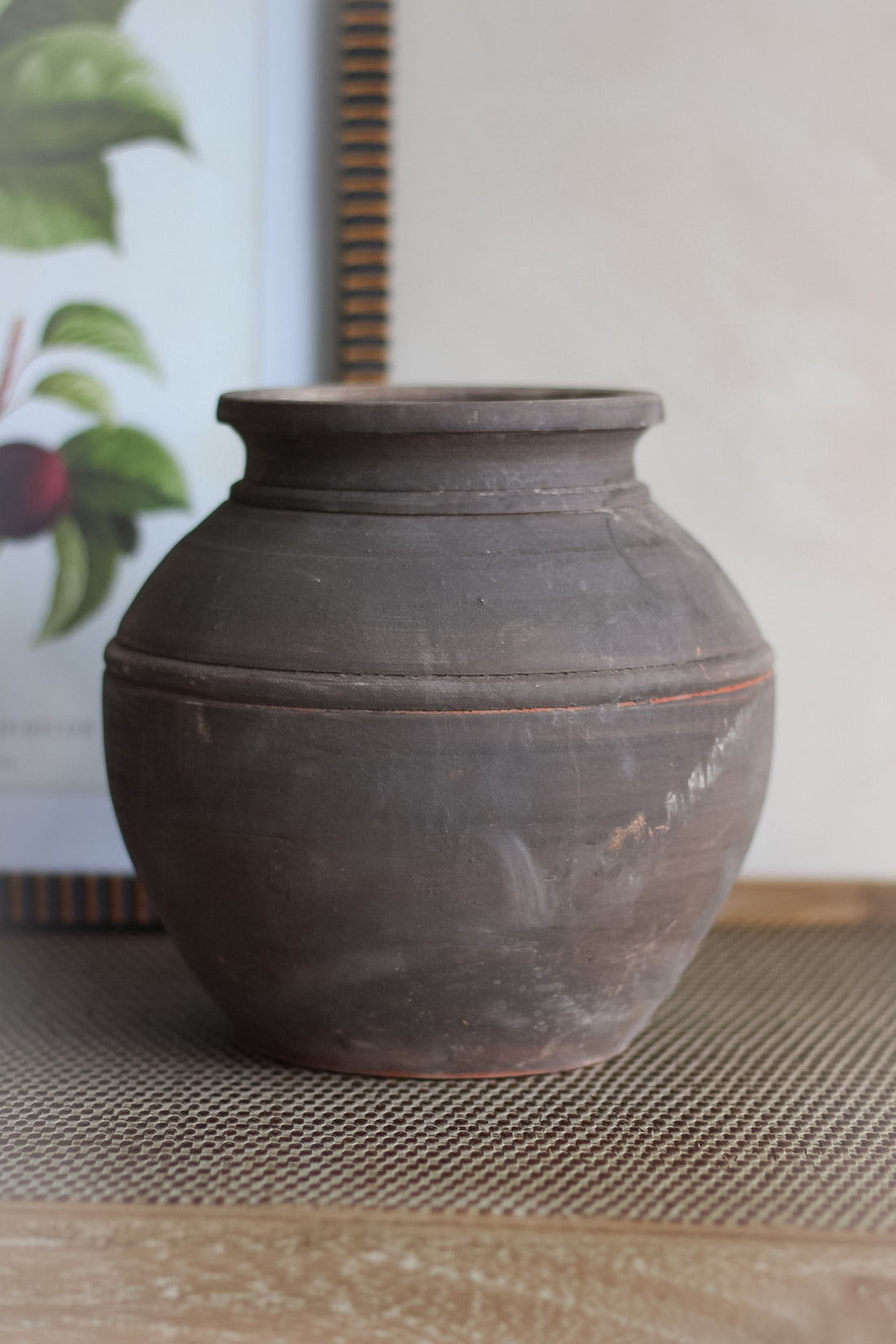 Brown clay pot on a textured surface with a blurred background