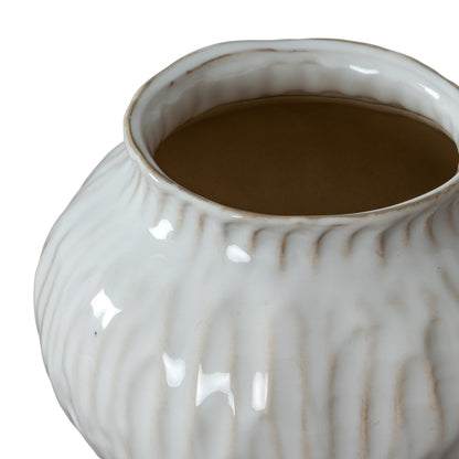 White ceramic pot with textured surface containing a brown liquid on a white background