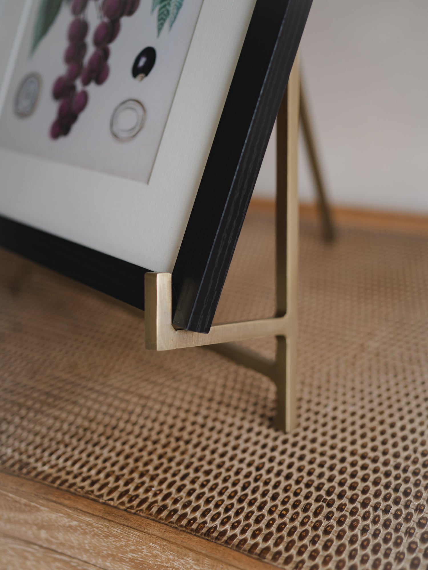 Close-up of a picture frame with a gold easel stand on a textured surface