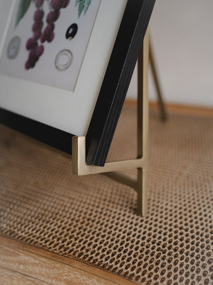 Close-up of a picture frame with a gold easel stand on a textured surface