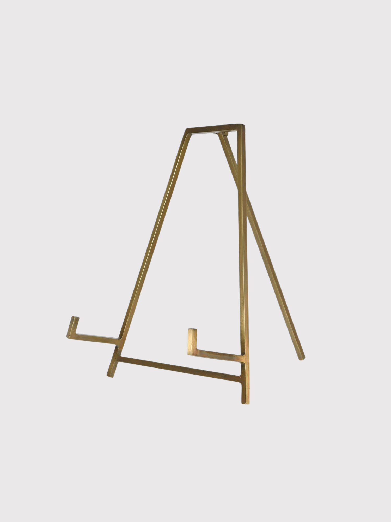 Gold metal antique brass easel on a light gray background