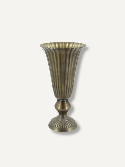 A vintage-style fluted metal vase with a flared rim and pedestal base, finished in an antique bronze or brass tone, shown against a plain light gray background.