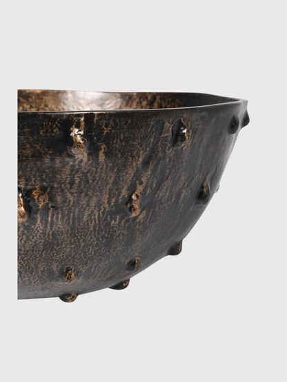 Decorative metal bowl with rivets on a light gray background