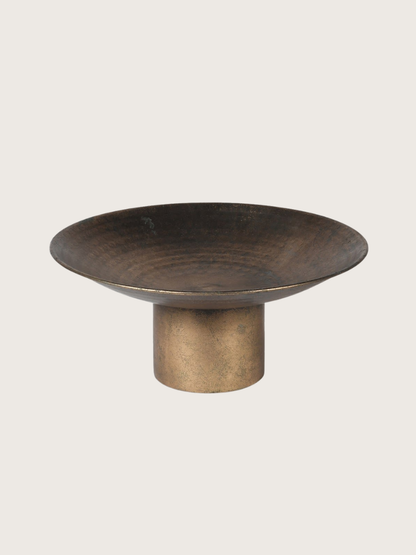 Bronze-colored bowl on a stand against a light gray background