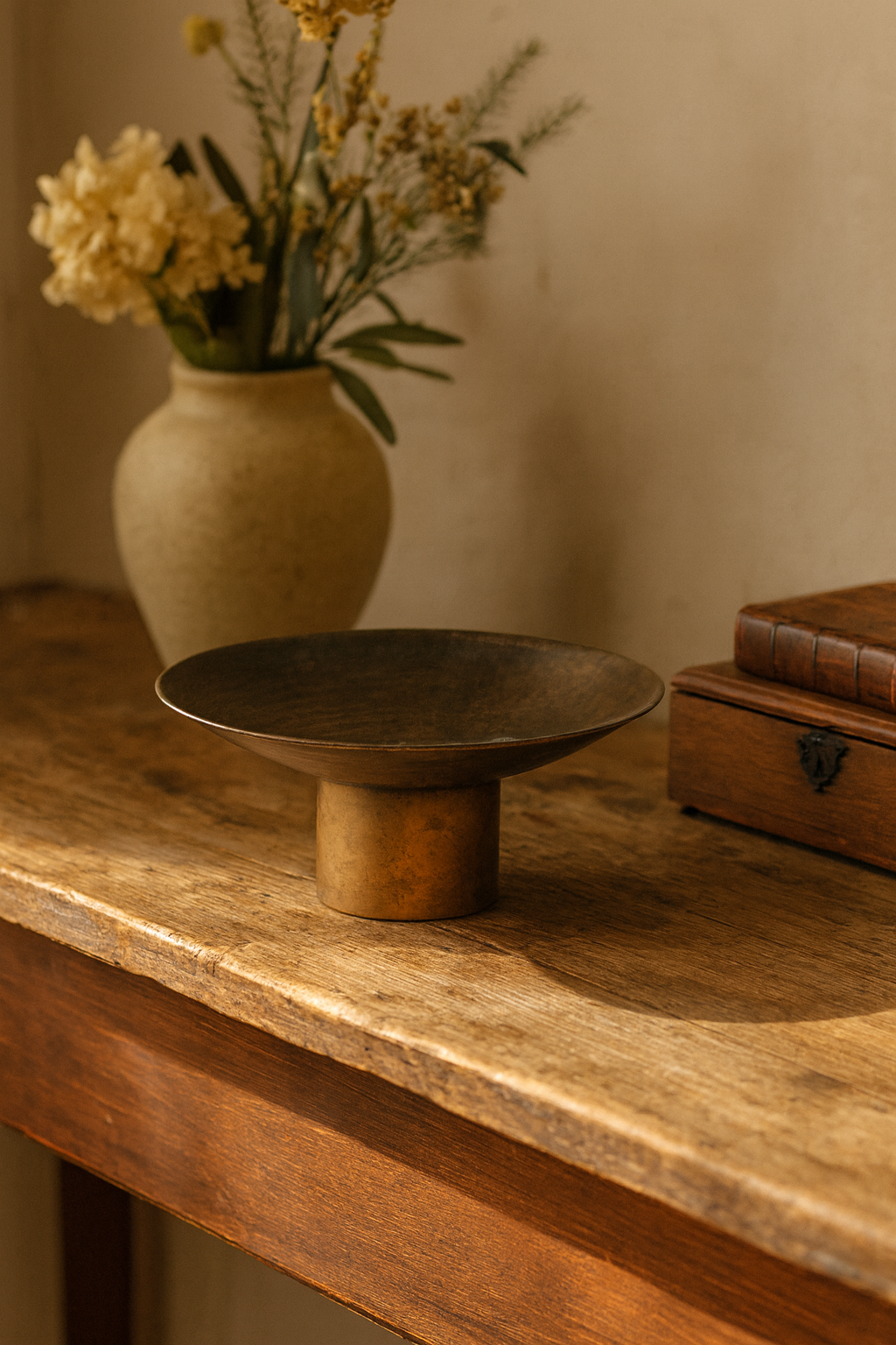 Decorative wooden table with a vase of flowers and a wooden bowl.