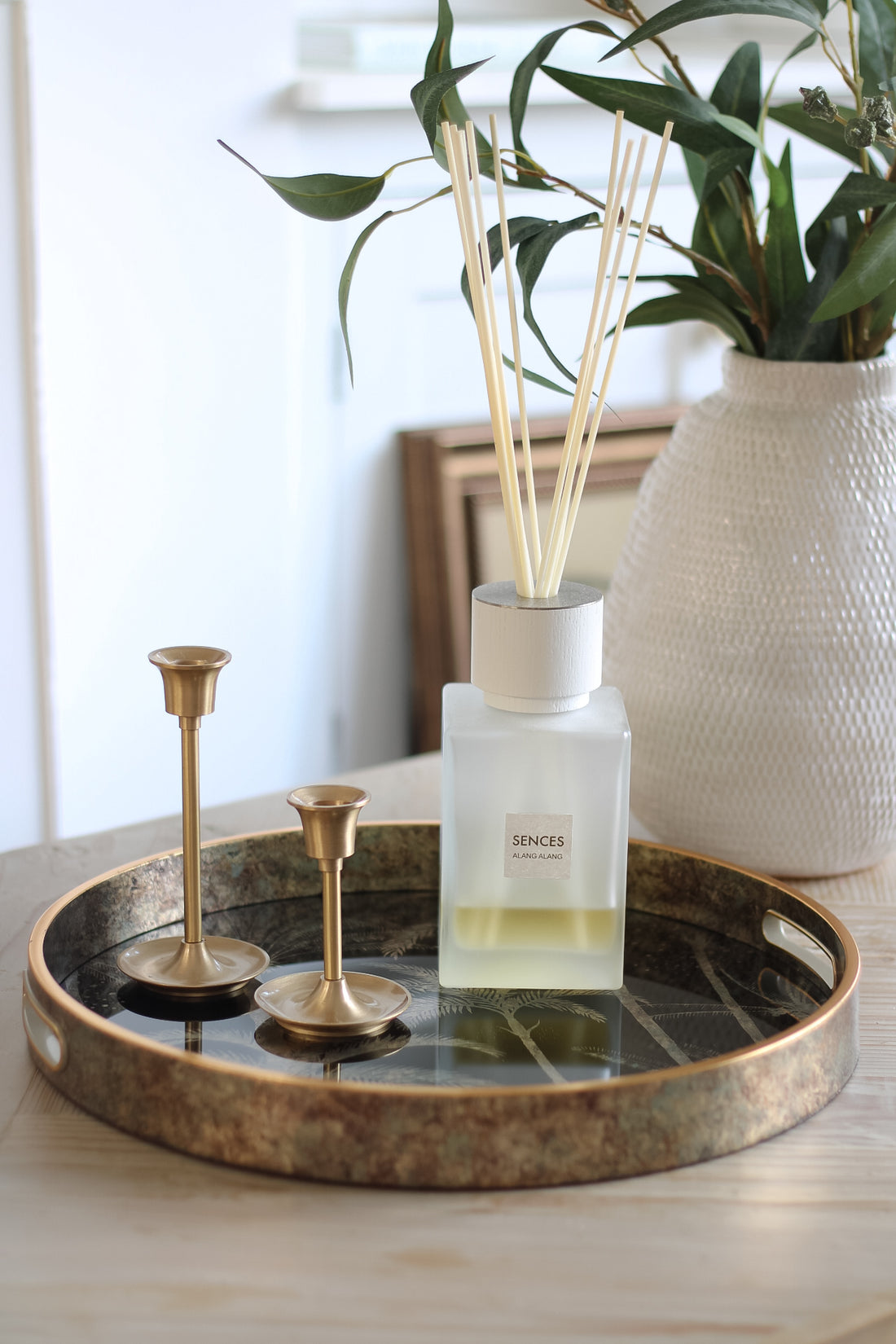 coffee table styling idea with antique gold palm tree round tray, gold candle stick and luxury reed diffuser