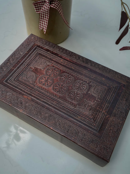 Decorative storage book box with intricate carvings on a white surface