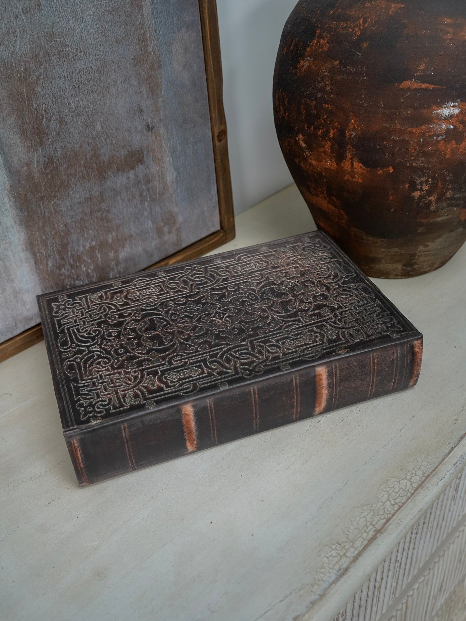 Decorative storage book box with intricate carvings on a textured surface