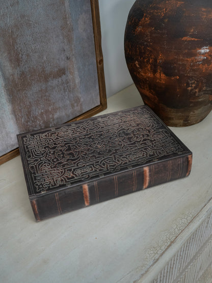 Decorative storage book box with intricate carvings on a textured surface